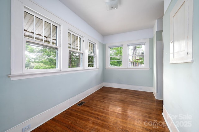 spare room featuring baseboards, visible vents, and dark wood finished floors