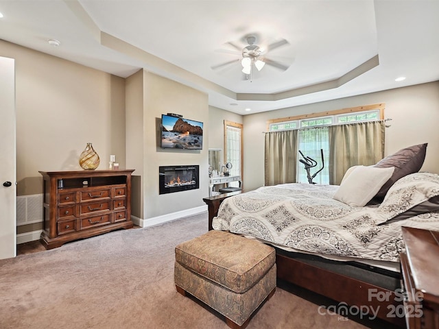 1140 Fern Hill Rd, Mooresville, NC 28117 - bedroom with carpet, a tray ceiling, a glass covered fireplace, baseboards, and recessed lighting