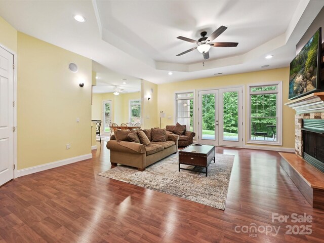 1140 Fern Hill Rd, Mooresville, NC 28117 - living area with a ceiling fan, a tray ceiling, a stone fireplace, wood finished floors, and recessed lighting