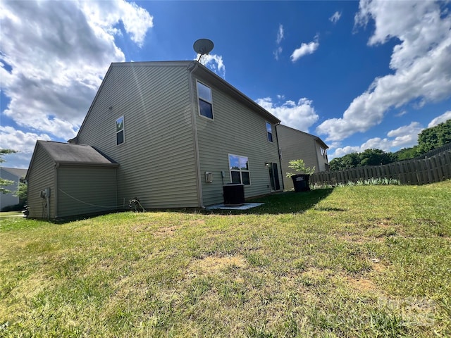 view of side of home featuring fence, a lawn, and central AC
