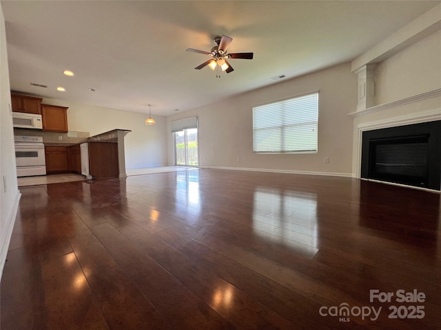 unfurnished living room with recessed lighting, dark wood-style flooring, a ceiling fan, baseboards, and a glass covered fireplace
