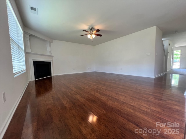 unfurnished living room featuring visible vents, a fireplace, ceiling fan, and dark wood-style floors