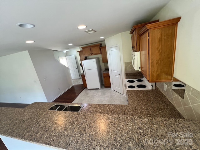 kitchen with recessed lighting, white appliances, a sink, a peninsula, and brown cabinets