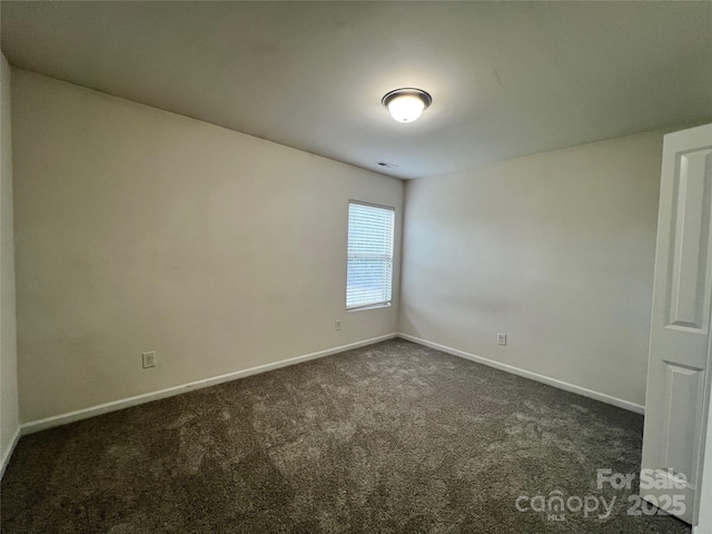 unfurnished room featuring dark colored carpet and baseboards