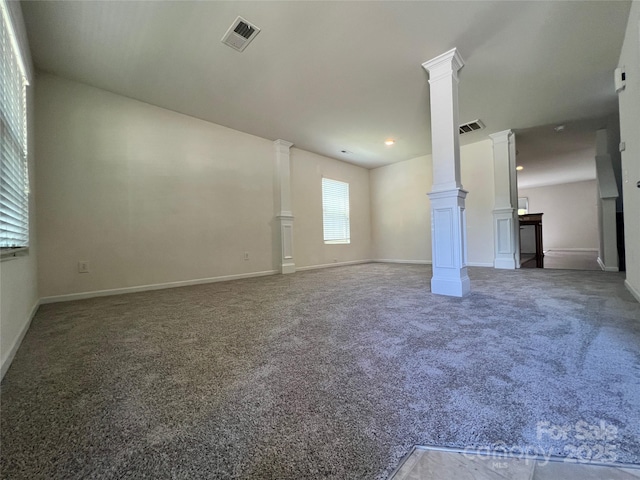 carpeted empty room featuring visible vents, baseboards, and decorative columns