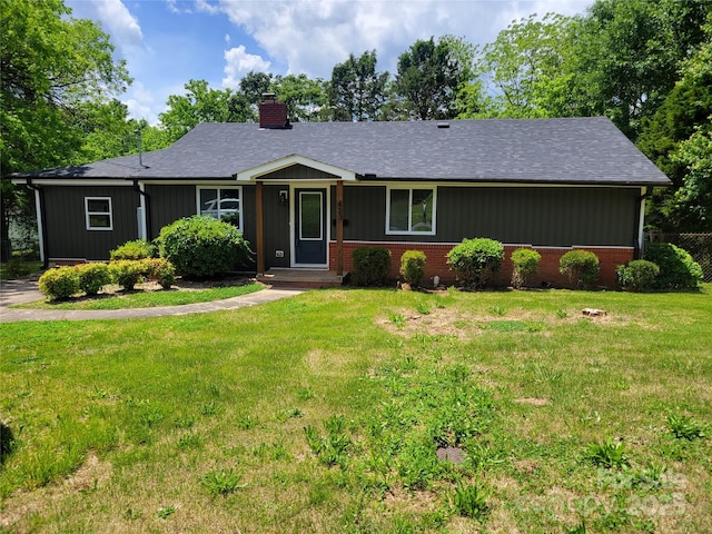 single story home with a chimney, a front yard, roof with shingles, and brick siding