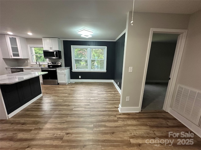 kitchen featuring stainless steel appliances, a sink, crown molding, white cabinetry, and glass insert cabinets