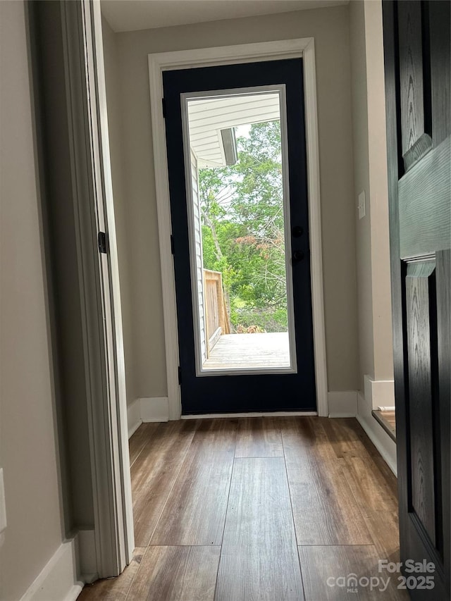 doorway to outside with wood finished floors and baseboards