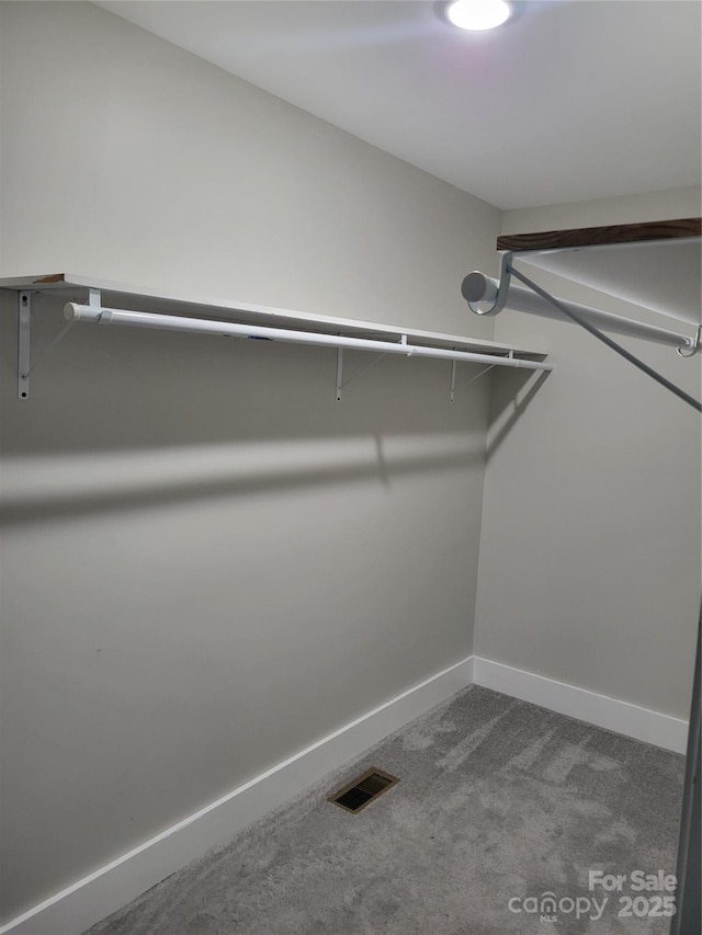 walk in closet featuring dark carpet