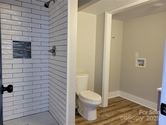 full bathroom with wood finished floors, toilet, a shower stall, and baseboards