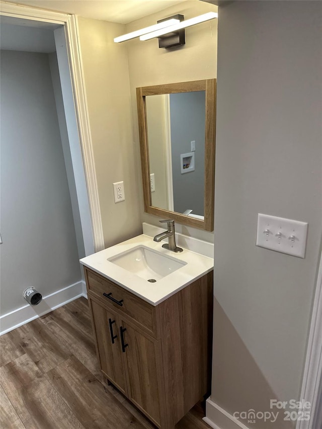 bathroom with wood finished floors, vanity, and baseboards