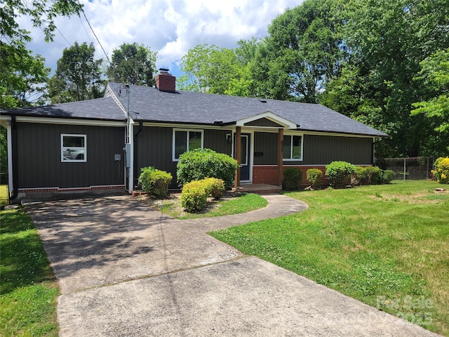 ranch-style house featuring a chimney, roof with shingles, and driveway