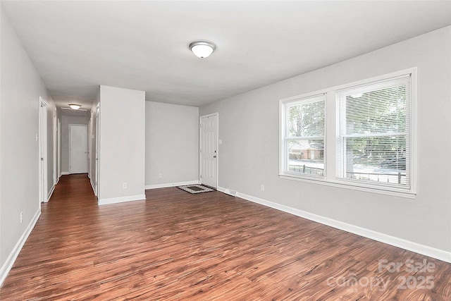 empty room featuring baseboards and dark wood finished floors