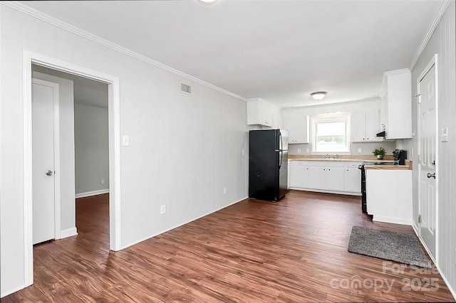 kitchen with freestanding refrigerator, electric range oven, white cabinets, and a sink
