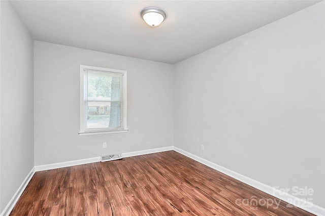 spare room featuring dark wood-style flooring and baseboards