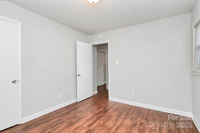 unfurnished bedroom with wood finished floors and baseboards