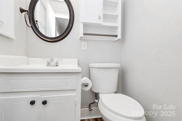 half bathroom with vanity, toilet, and wood finished floors