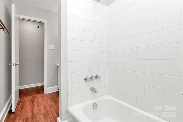full bath with baseboards, wood finished floors, and bathtub / shower combination
