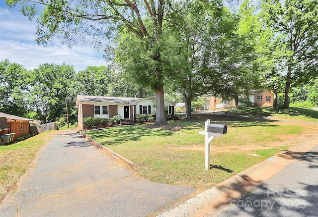 view of front of house with brick siding, a front yard, and aphalt driveway