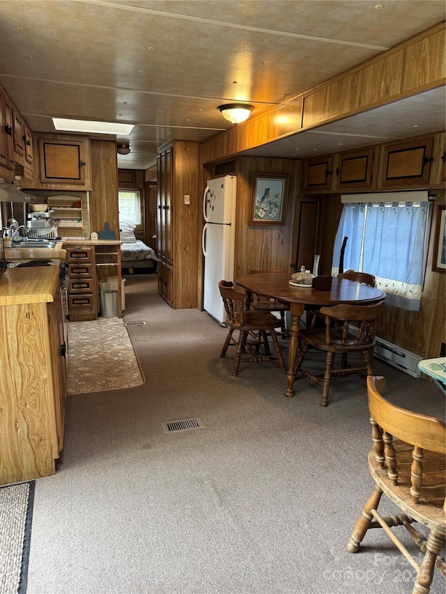 dining area featuring light colored carpet, wood walls, and visible vents