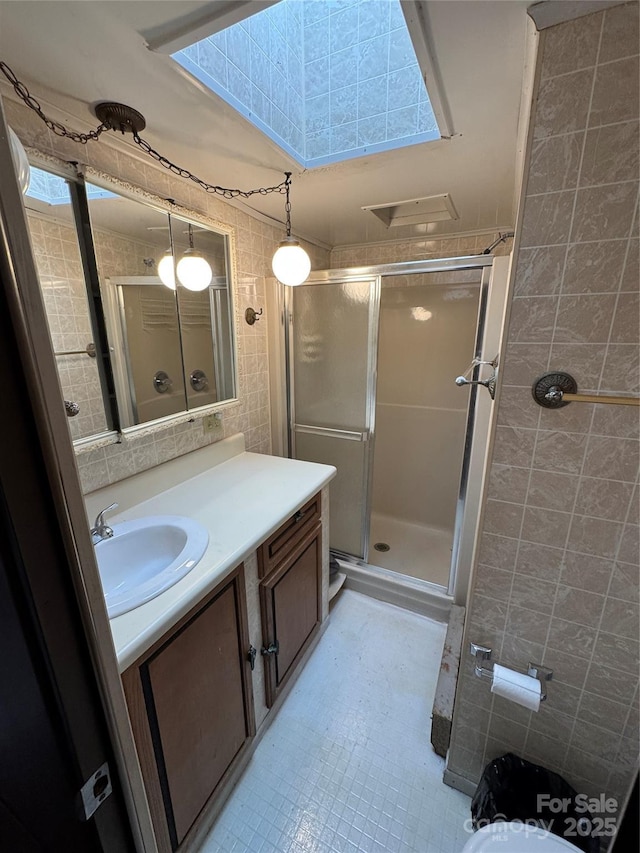 full bathroom with tile patterned floors, tile walls, vanity, and a stall shower