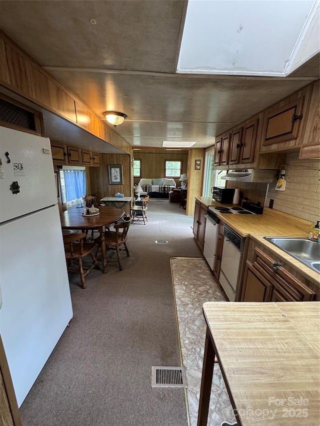 kitchen with carpet flooring, a sink, visible vents, white appliances, and light countertops