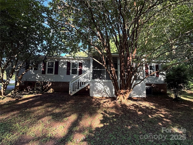 rear view of property featuring a sunroom and stairs