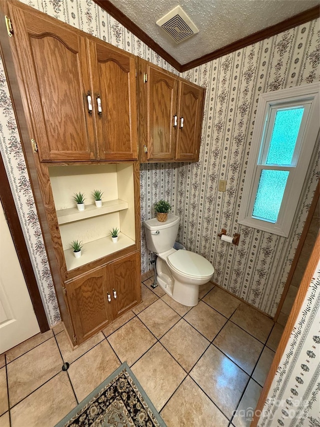 bathroom with toilet, ornamental molding, wallpapered walls, a textured ceiling, and tile patterned flooring