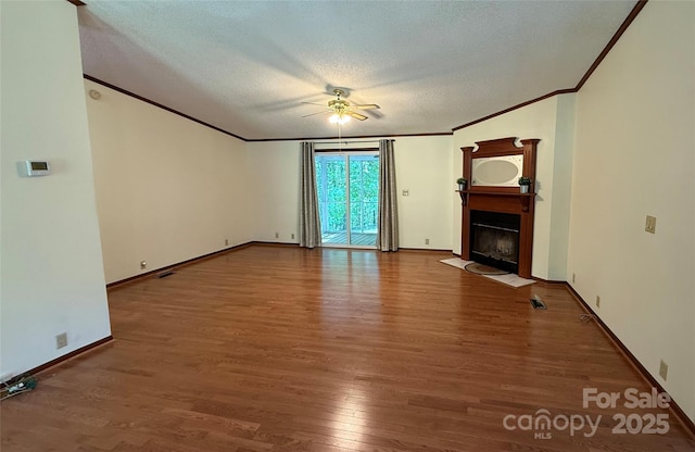 unfurnished living room with crown molding, ceiling fan, wood finished floors, a fireplace with flush hearth, and a textured ceiling