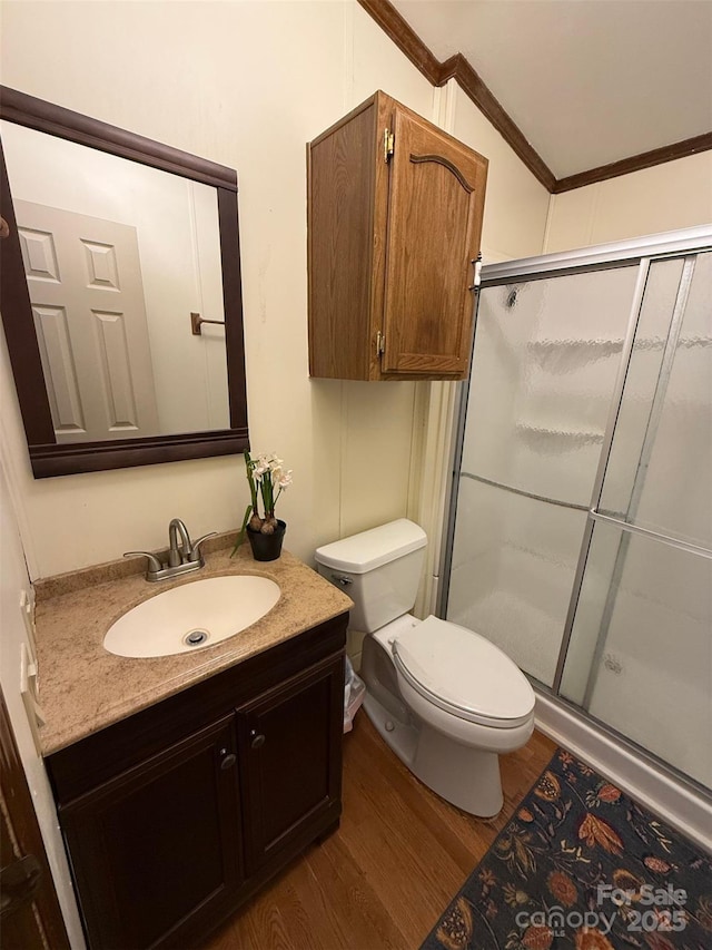 full bathroom featuring wood finished floors, toilet, a stall shower, vanity, and ornamental molding