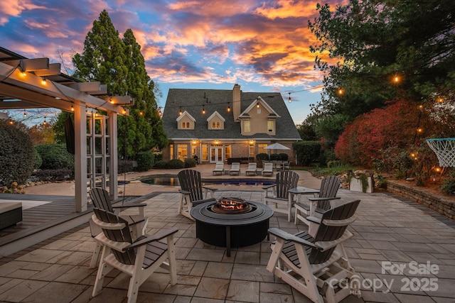 18823 Peninsula Cove Ln, Cornelius, NC 28031 - patio terrace at dusk featuring a fire pit, an outdoor pool, a patio area, a storage structure, and a jacuzzi