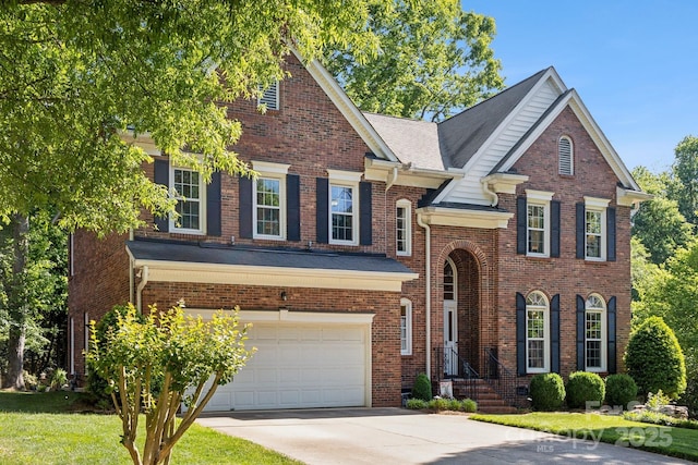 view of front of home featuring a front lawn, driveway, brick siding, and an attached garage