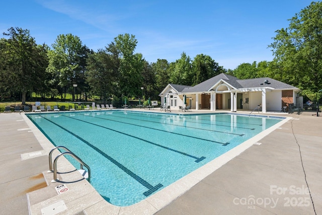 community pool with fence, a patio, and view of scattered trees