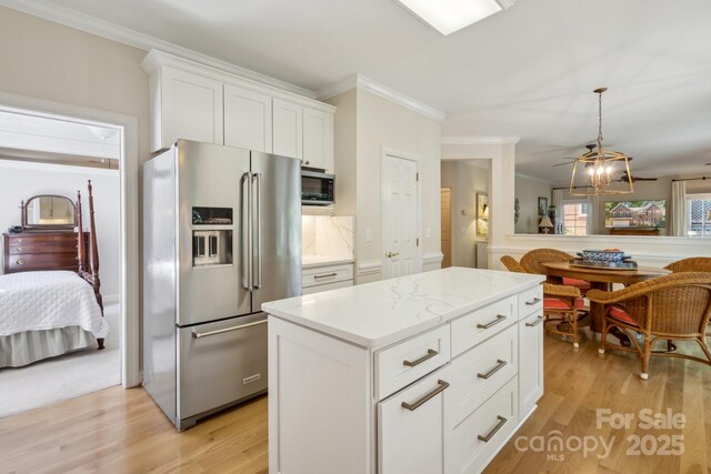 kitchen with high quality fridge, a center island, light wood-style flooring, white cabinets, and ornamental molding