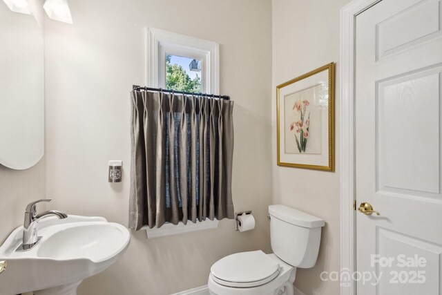 bathroom featuring a sink, toilet, and baseboards