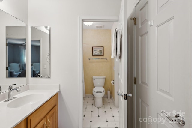 bathroom featuring toilet, baseboards, visible vents, vanity, and connected bathroom