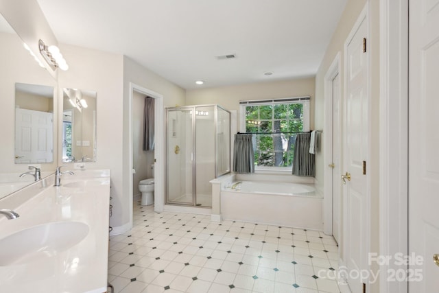 bathroom with toilet, a bath, a shower stall, double vanity, and baseboards