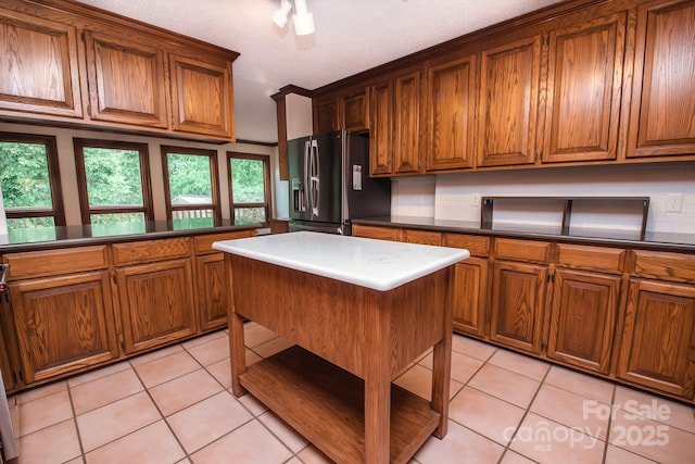 kitchen featuring fridge with ice dispenser, brown cabinets, and light tile patterned floors