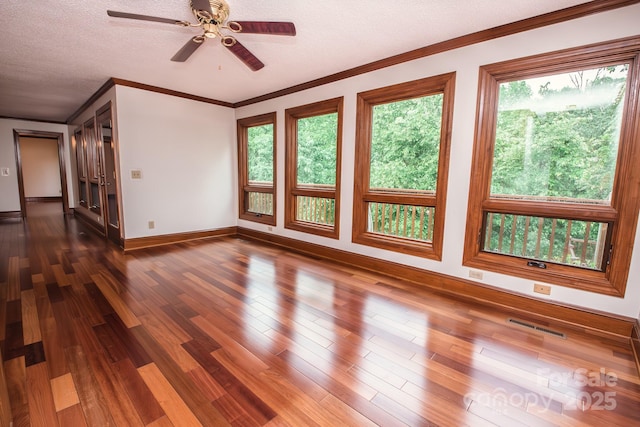 empty room with baseboards, a ceiling fan, ornamental molding, dark wood-style floors, and a textured ceiling