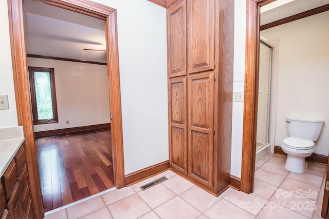 full bath featuring toilet, baseboards, a shower stall, ornamental molding, and wood finished floors
