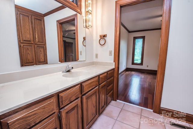 bathroom featuring ornamental molding, vanity, baseboards, and tile patterned flooring