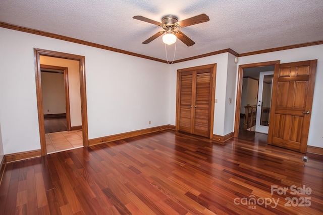 unfurnished bedroom featuring wood finished floors, a textured ceiling, baseboards, a closet, and ornamental molding