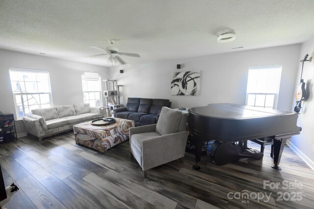 living area with a textured ceiling, baseboards, wood finished floors, and a ceiling fan