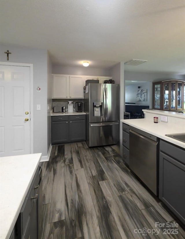 kitchen featuring stainless steel appliances, gray cabinetry, dark wood-style flooring, visible vents, and light countertops