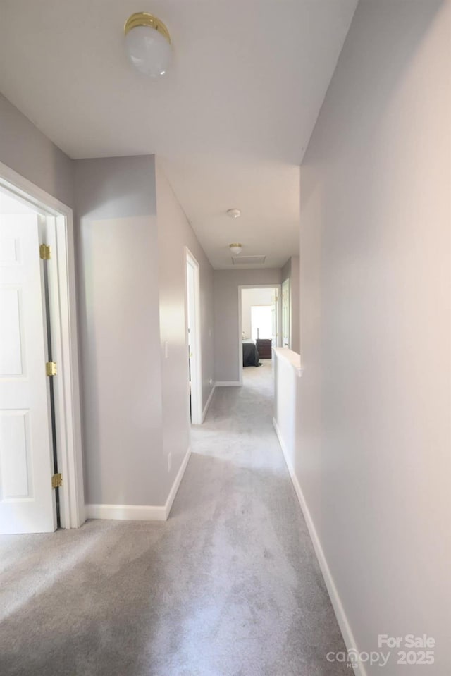 hallway featuring light carpet and baseboards