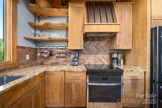 55 Maynards Way, Hendersonville, NC 28792 - kitchen featuring appliances with stainless steel finishes, decorative backsplash, custom range hood, brown cabinetry, and light stone countertops