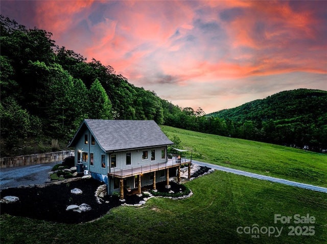55 Maynards Way, Hendersonville, NC 28792 - rear view of house with a deck, a lawn, a wooded view, and a shingled roof