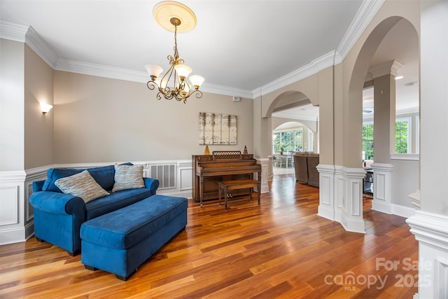 10452 Quiet Bay Ct, Charlotte, NC 28278 - living area with arched walkways, ornamental molding, wood finished floors, a wainscoted wall, and a chandelier