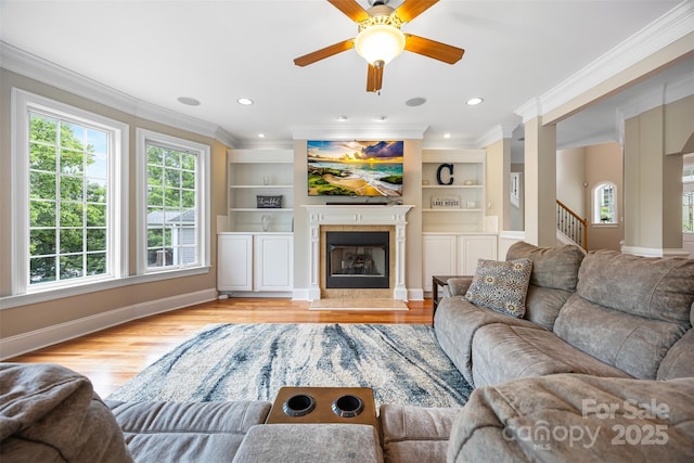 10452 Quiet Bay Ct, Charlotte, NC 28278 - living area featuring ornamental molding, light wood-style flooring, a fireplace, a ceiling fan, and built in features