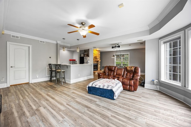 10452 Quiet Bay Ct, Charlotte, NC 28278 - living area featuring light wood-style floors, a fireplace, ceiling fan, baseboards, and crown molding